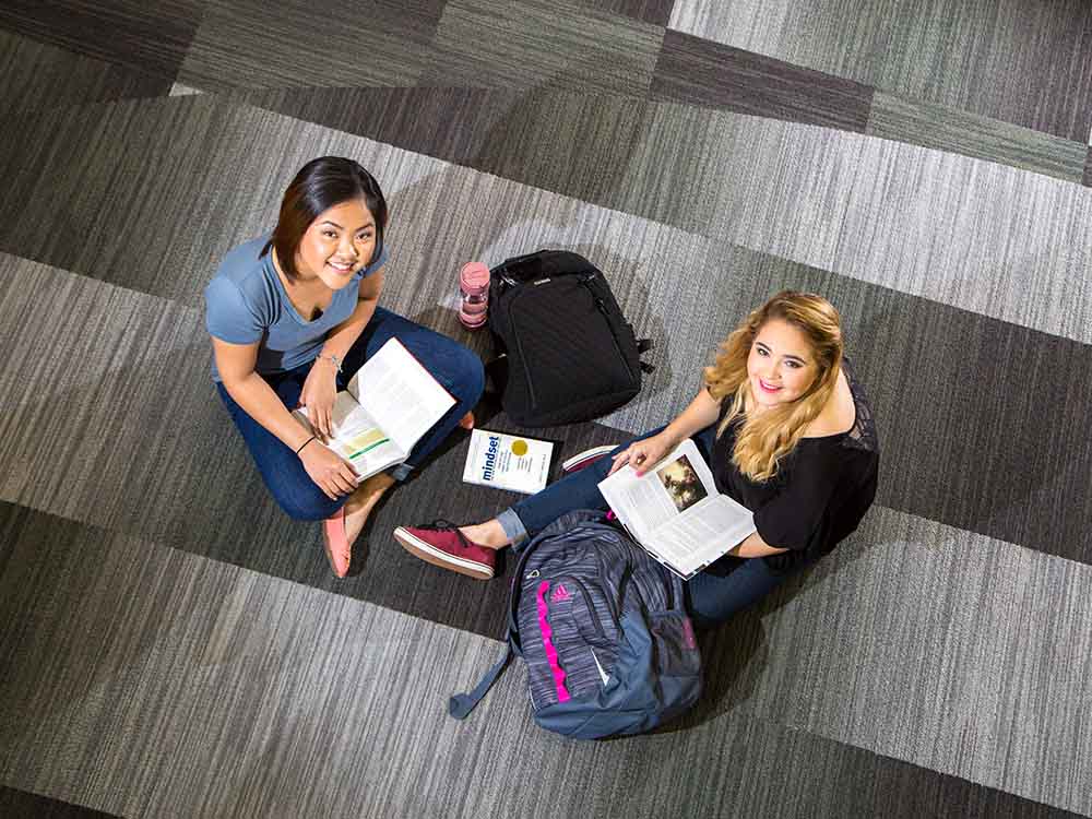 Two San Jacinto College students sitting on floor studying.