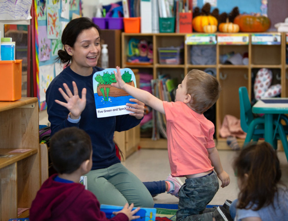 Teacher and children sitting at a table working on a learning activity