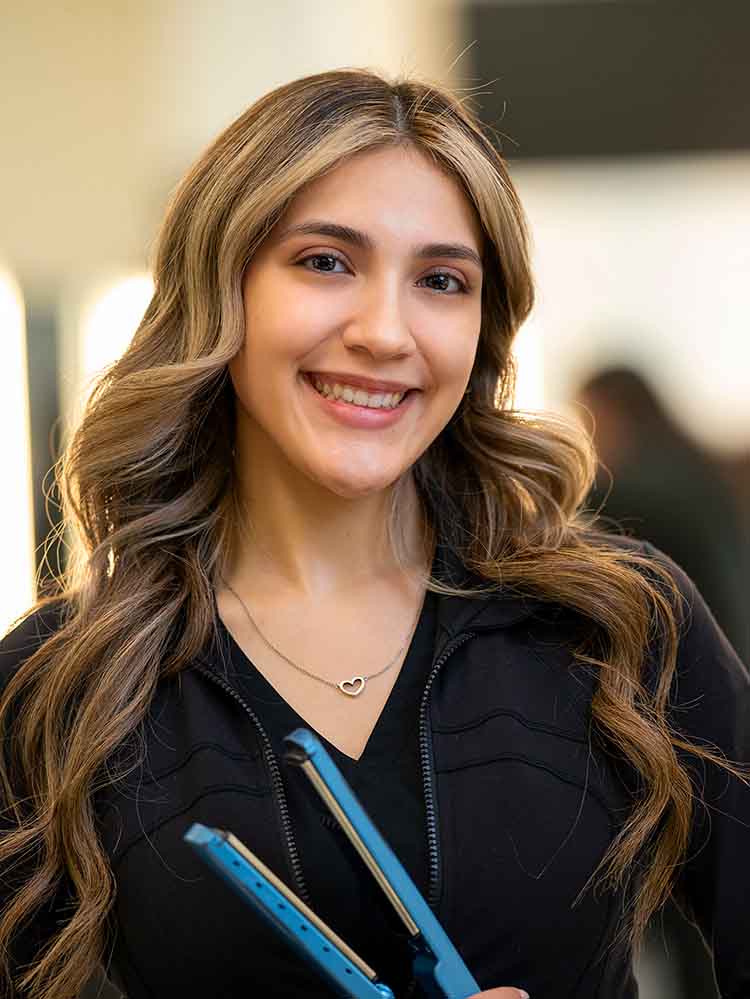 female cosmetology student holding hair straightener
