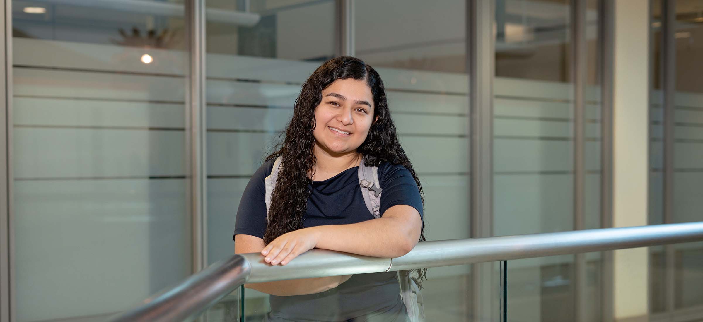 female san jac student smiling for camera leaning over railing