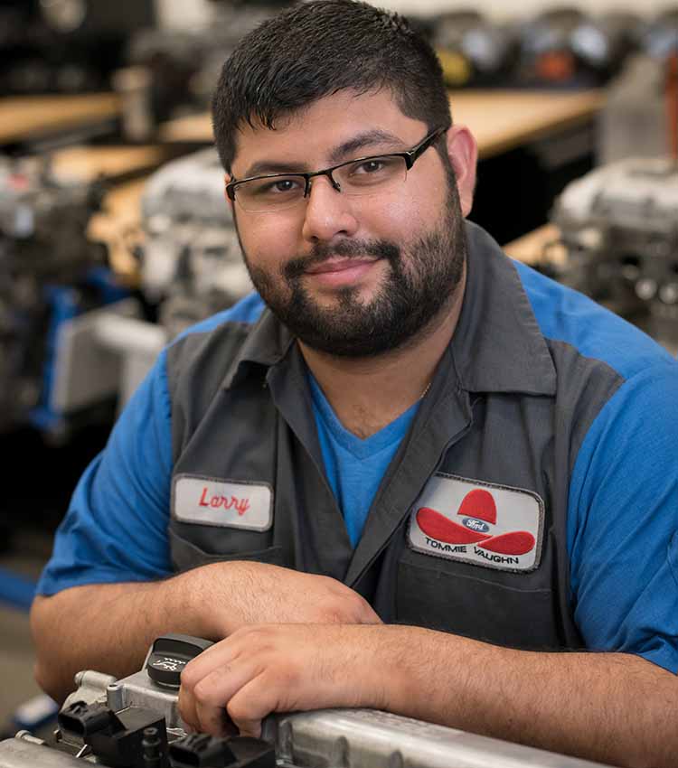 ford asset student smiling for camera while working on gas cap area of car
