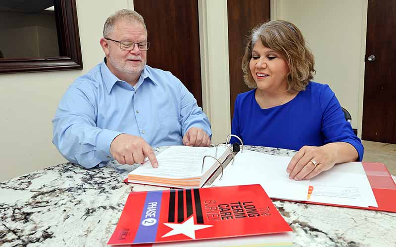 Long-term care administrator and intern reviewing policies at a conference room table