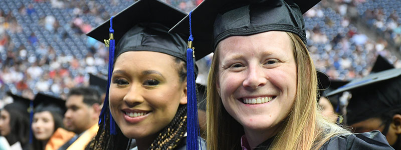 Two girls in graduation regalia at commencement